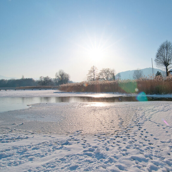 Blick auf den zum Teil zugefrorenen und schneebedeckten Ossiacher See in Kärnten.